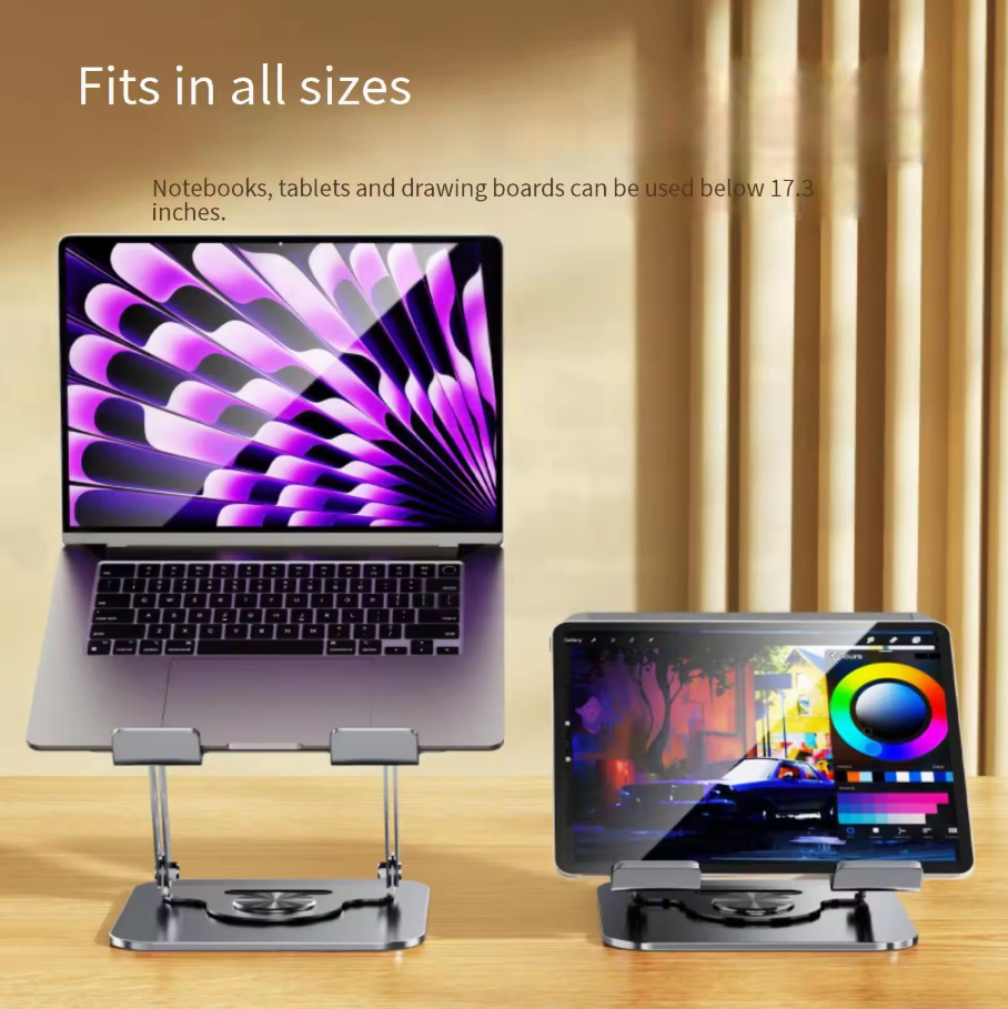 Two silver aluminum laptop and tablet stands shown on a wooden surface against a warm beige curtain backdrop. One stand holds an open laptop and the other holds a tablet, with text noting they fit all sizes and that notebooks, tablets, and drawing boards can be used below 17.