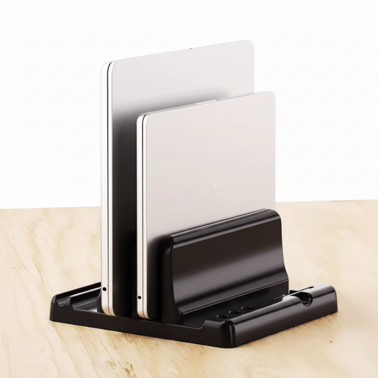 A black tablet stand holding two silver tablets upright, placed on a light wood surface against a white background.