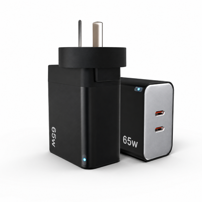 A 65W dual-port USB-C wall charger shown from two angles: one view showing the black plug body with silver prongs and '65W' text, and another showing the black and silver face with two USB-C ports and small blue indicator lights.