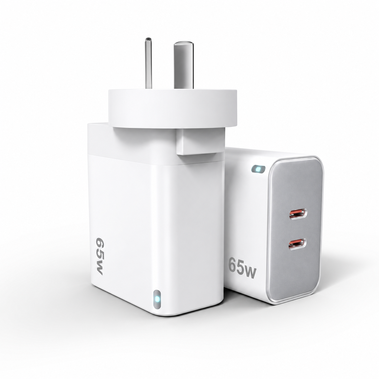 A 65W dual USB-C wall charger shown from two angles: one facing forward with a two-pin plug, and one showing the side with two USB-C ports. The charger is white with a silver side panel and small blue LED indicator lights.