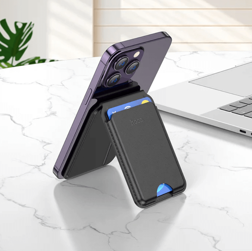 Phone case with card holder on a marble surface with laptop and plant in background