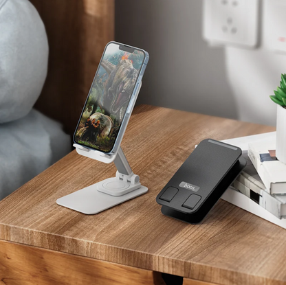 A dual-mode phone stand and charger dock shown on a wooden table, with one white version holding a smartphone and one black version lying beside it.