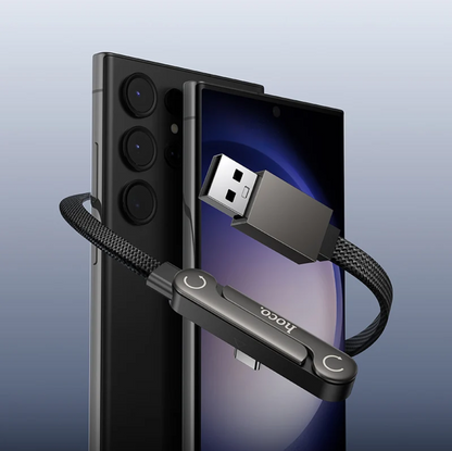 A black USB dongle with a braided cable and a USB-A connector, shown attached to a smartphone on a clean light blue gradient background. The dongle has the brand name 'booco' printed on it.