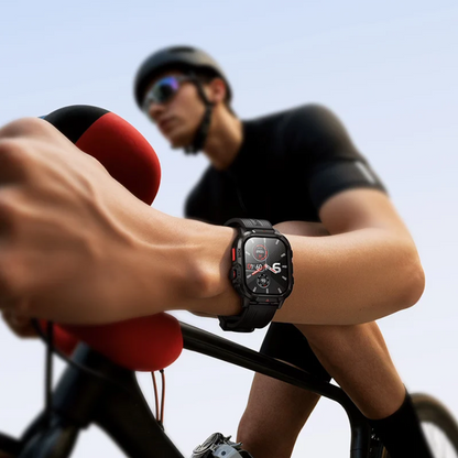 A close-up of a person riding a bicycle with a smartwatch on their wrist, wearing a black cycling jersey and helmet in the background.